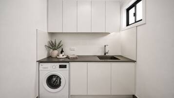 A compact laundry room with a washing machine, a sink, and cabinets.