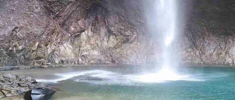 A waterfall in a natural setting with clear water and rocky surroundings.