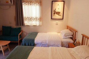 Une chambre avec deux lits, un canapé, une table et une fenêtre avec des rideaux.