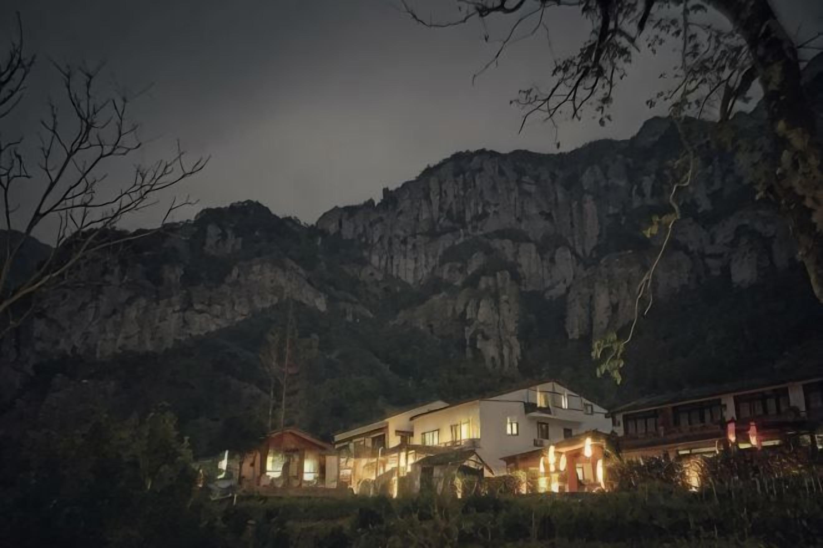 Un edificio grande con varios niveles, rodeado de terreno montañoso.