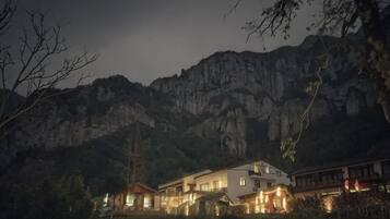 Un edificio grande con varios niveles, rodeado de terreno montañoso.