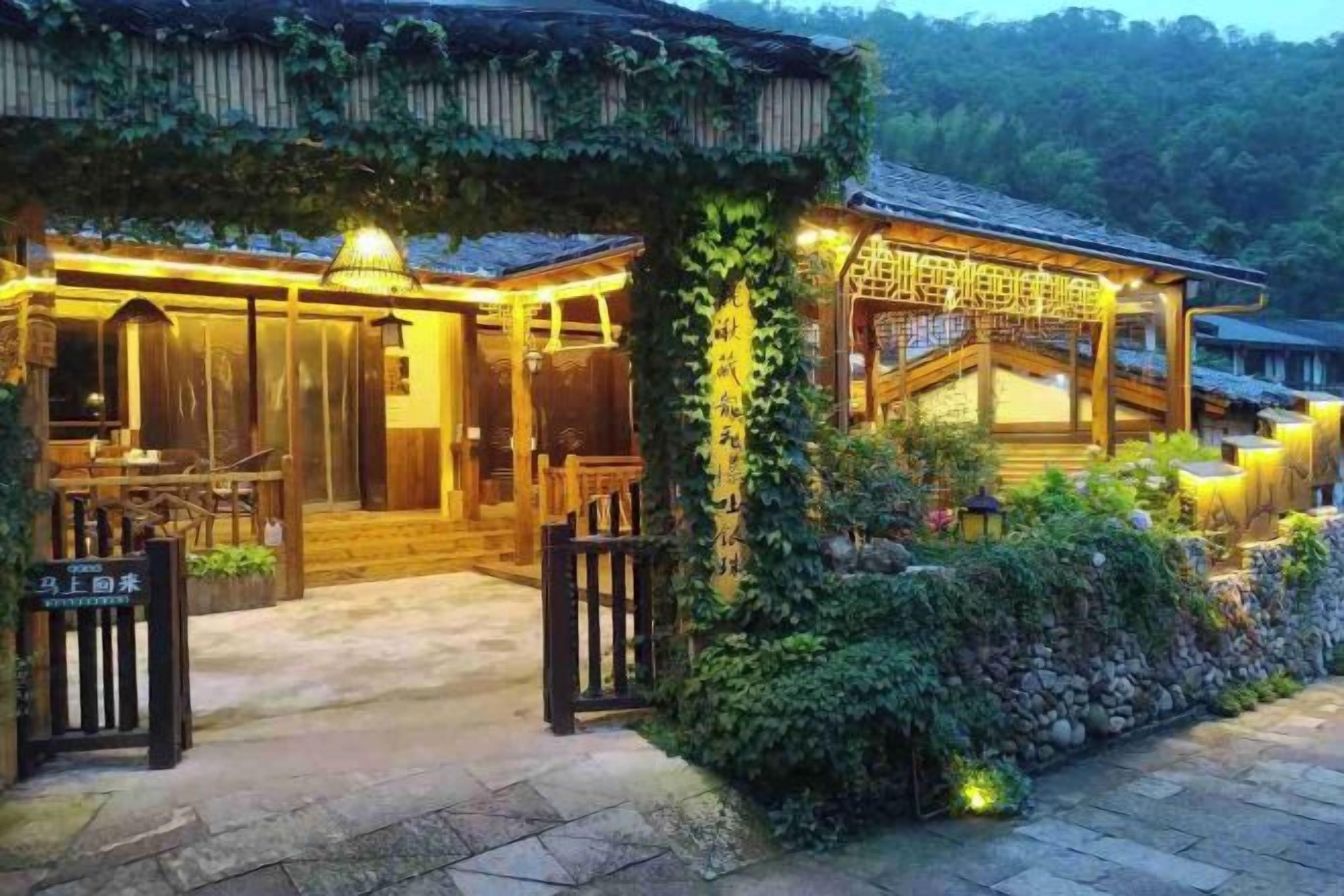 A traditional wooden building with a covered entrance and a stone pathway leading to the entrance.