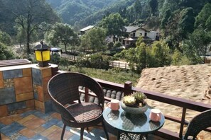 A balcony with a wicker chair, a small table with a potted plant, and a lantern. - Yandang Qiushui Shanshe Hostel (Yueqing)