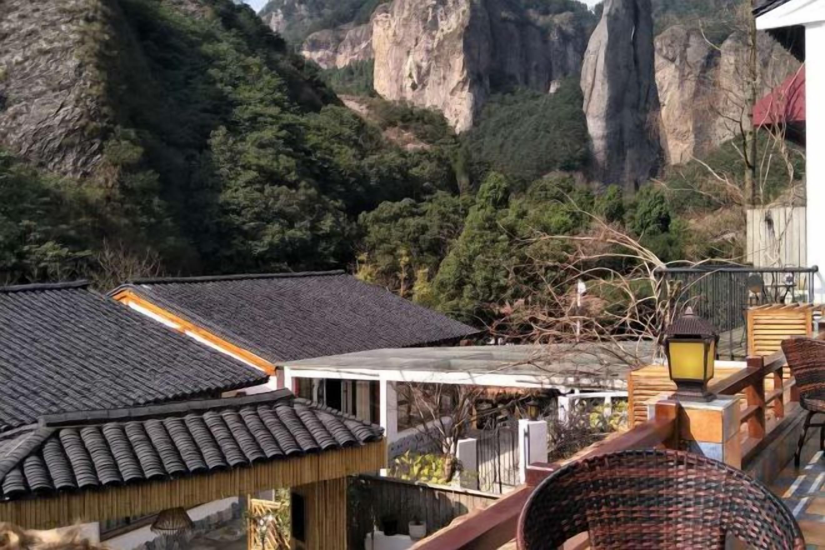 A traditional building with a tiled roof, surrounded by mountainous terrain and greenery.