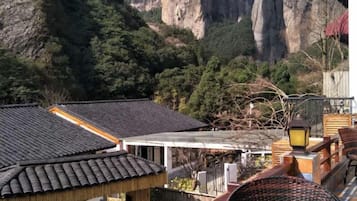 A traditional building with a tiled roof, surrounded by mountainous terrain and greenery.