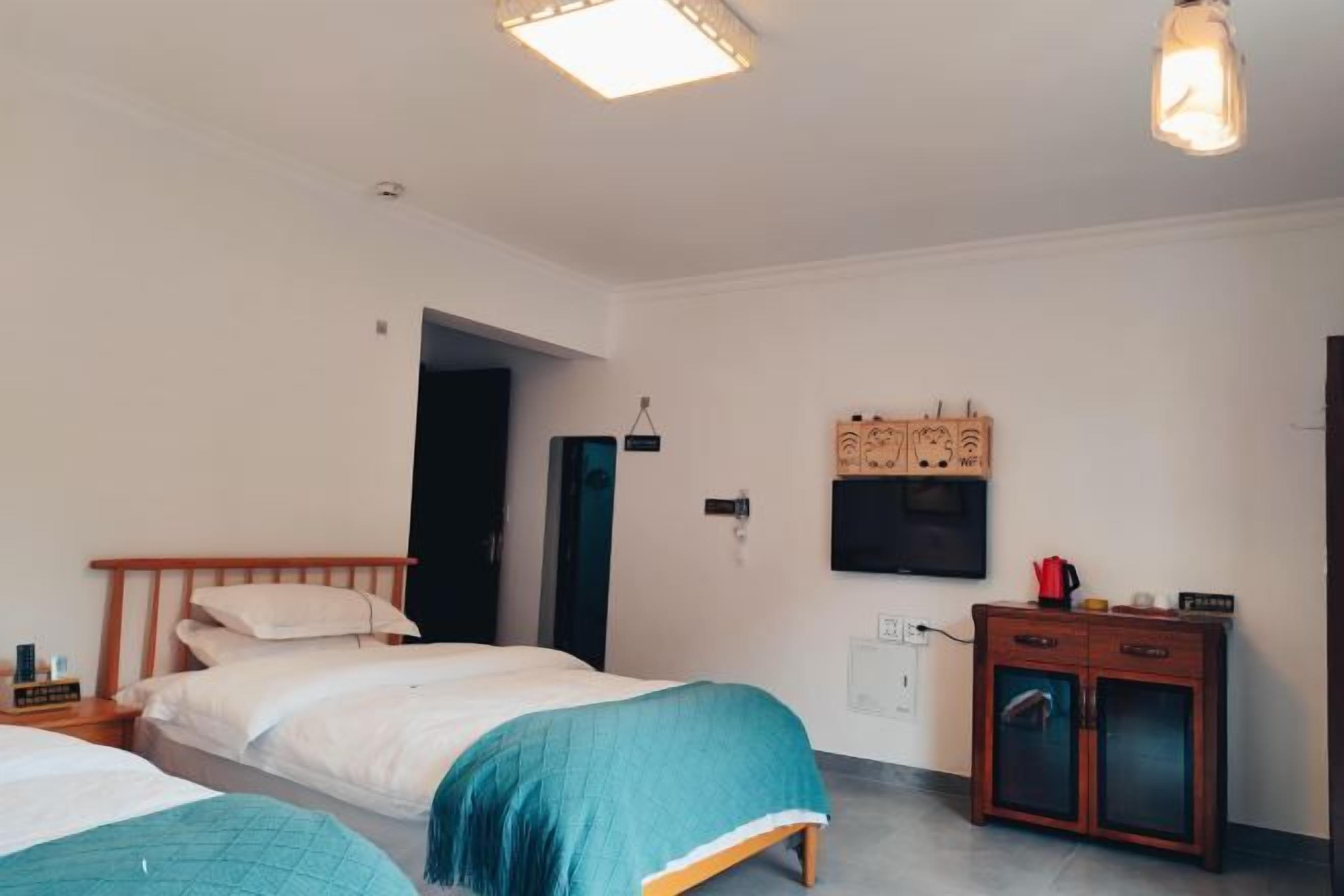 A bedroom with two beds, a wardrobe, a desk, and a television.