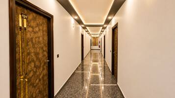 A hotel hallway with a marble floor, doors on both sides, and recessed lighting.