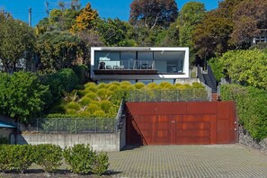 A modern building with a flat roof, large windows, and a balcony. - Beachfront Retreat - Architectural & Ocean Views (Nelson)