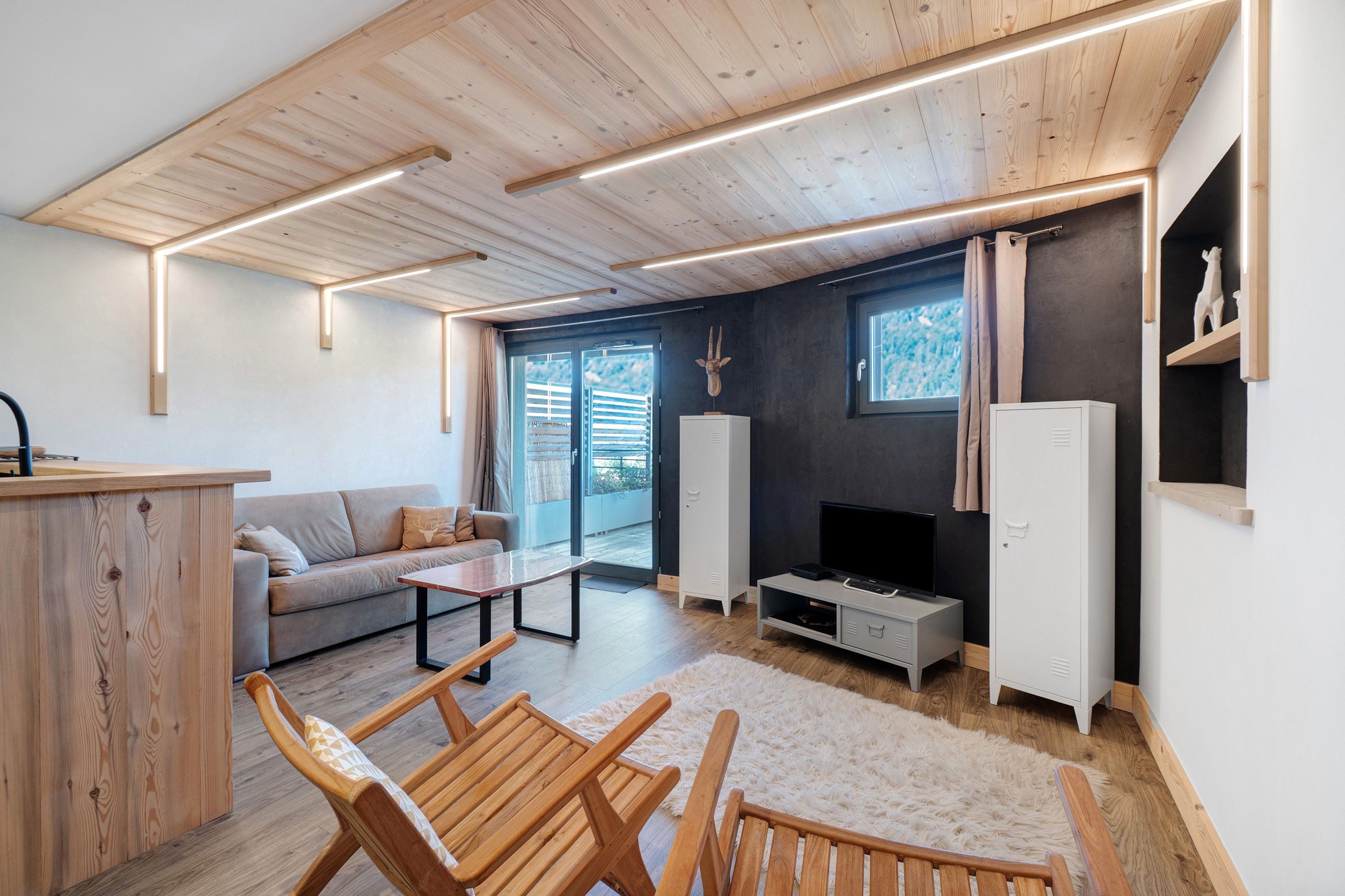 A modern living room with a sofa, wooden chairs, a coffee table, a TV, and a cabinet.