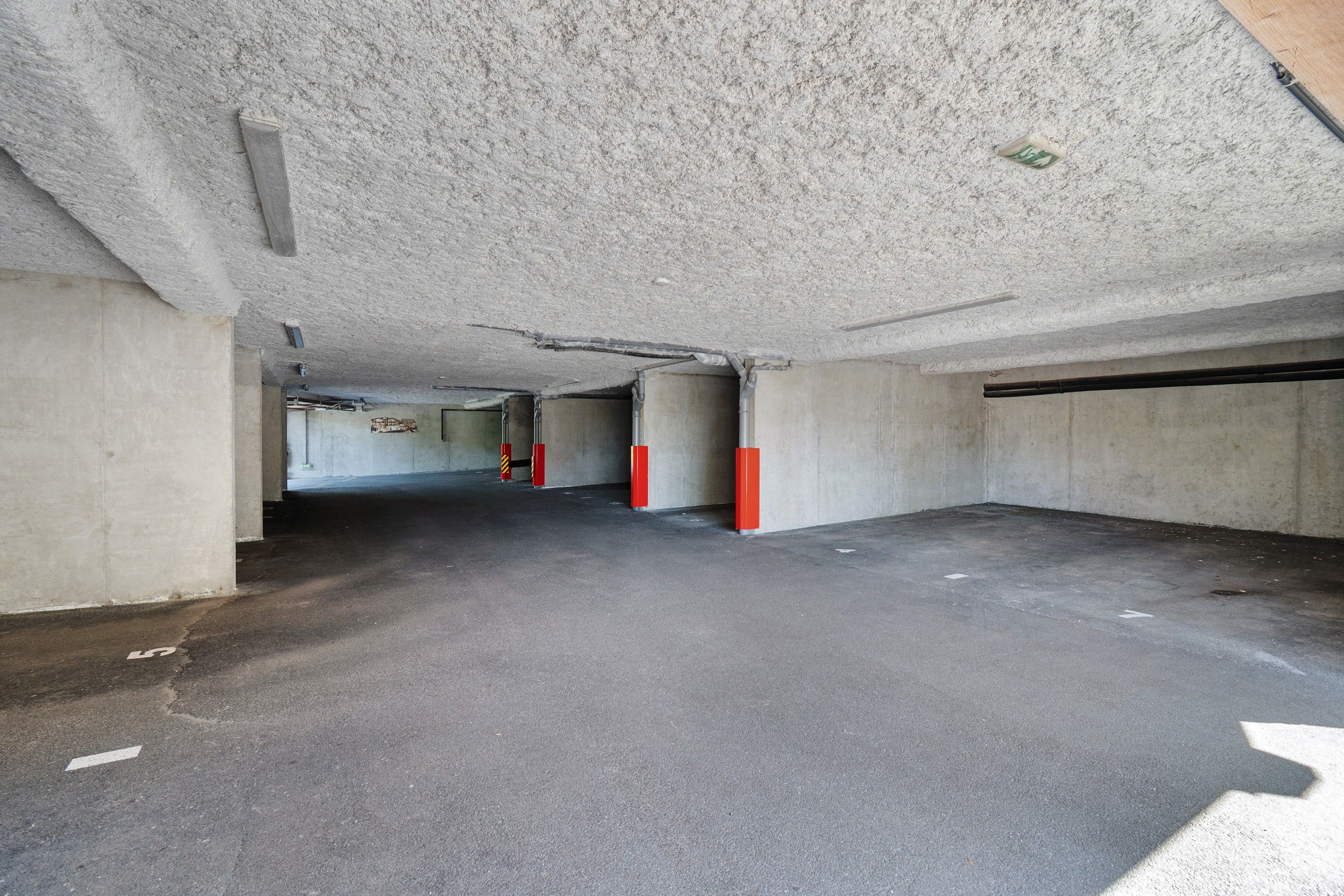 Eine Tiefgarage mit Betonwänden, ebener Decke und einem grauen Boden.