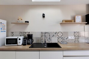 A modern kitchen with a black sink, white appliances, and decorative items on shelves.