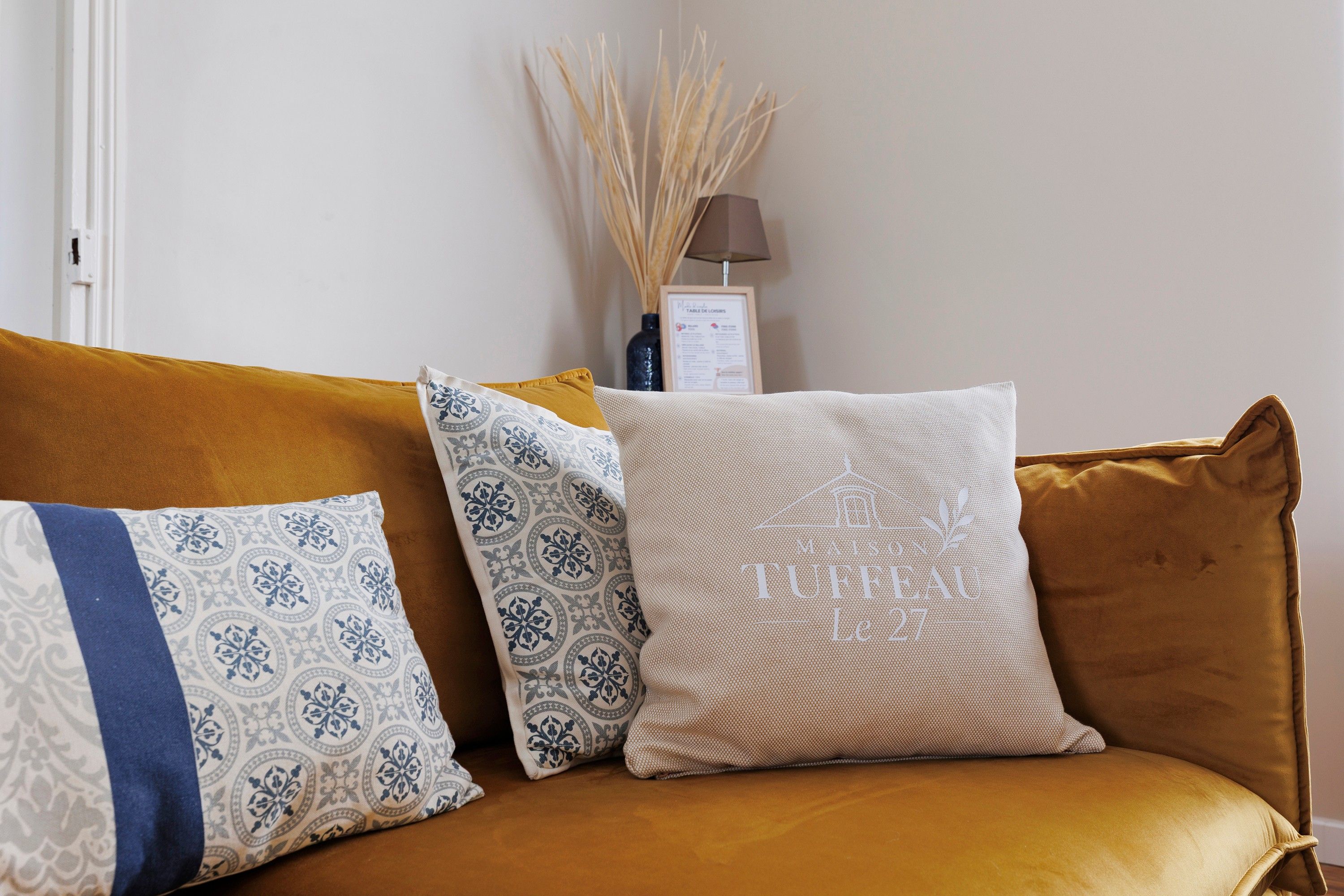 A sofa with patterned cushions and a framed menu on the wall behind.