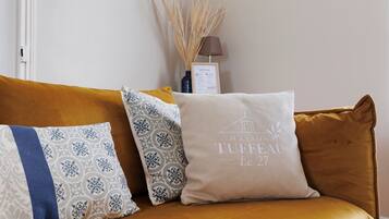 A sofa with patterned cushions and a framed menu on the wall behind.