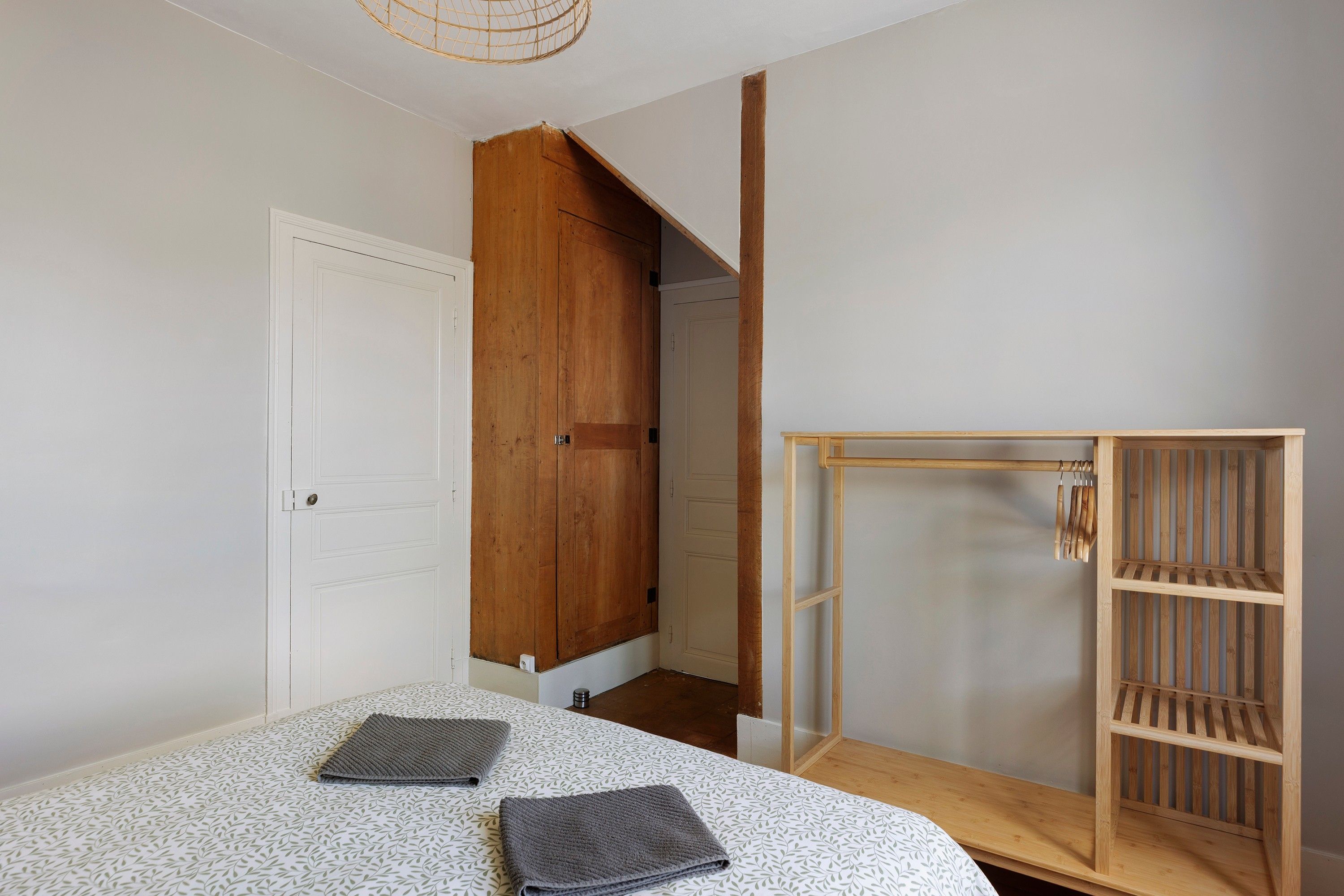 Een slaapkamer met een bed, een houten garderobe en een deur naar een trap.