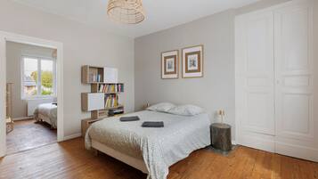 A bedroom with a bed, bedside tables, a lamp, a bookshelf, and framed pictures on the wall.