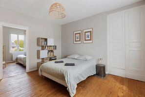 A bedroom with a bed, bedside tables, a lamp, a bookshelf, and framed pictures on the wall.