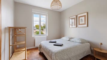 Una camera da letto con un letto, un armadio in legno, una finestra vista e due quadri appesi al muro.