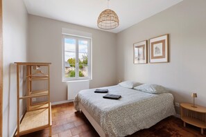 Ein Schlafzimmer mit einem Bett, einem Holzschrank, einem Fenster mit Aussicht und zwei gerahmten Bildern an der Wand.