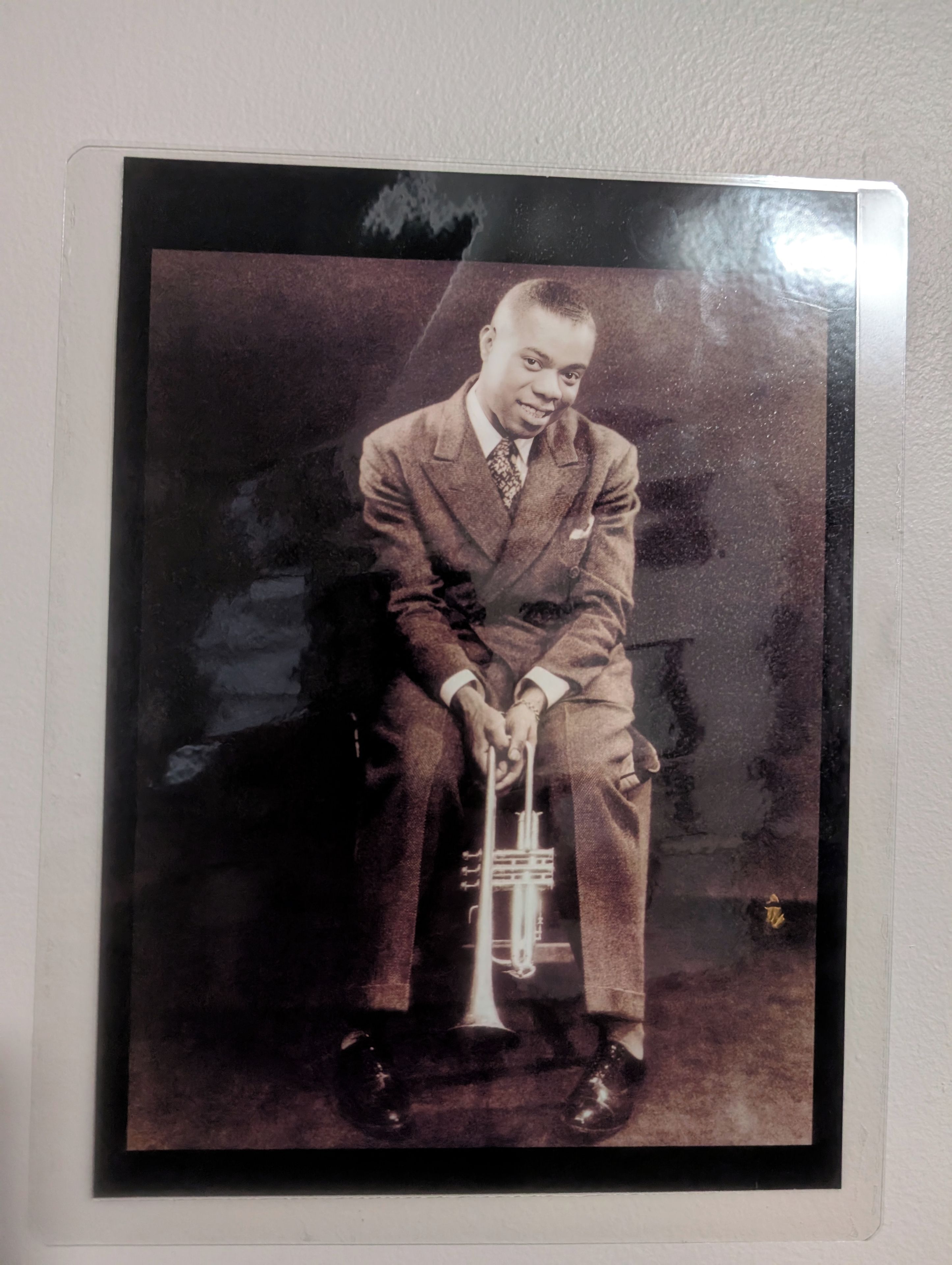 A vintage photograph of a person seated with a musical instrument.