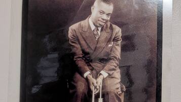 A vintage photograph of a person seated with a musical instrument.