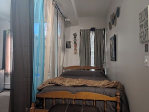 Een slaapkamer met een houten bed, gordijnen, een wandklok en een poster.