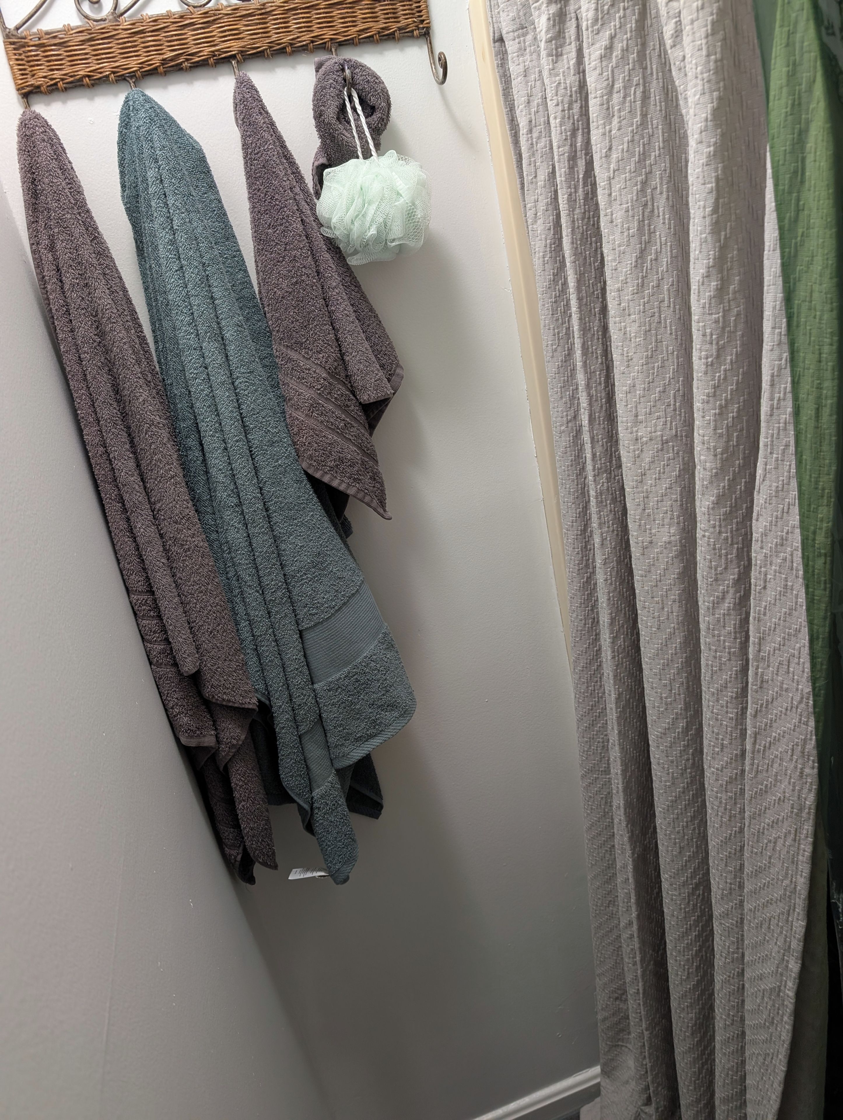 A wall with a hanging rack holding towels and a bathrobe.