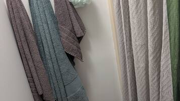 A wall with a hanging rack holding towels and a bathrobe.