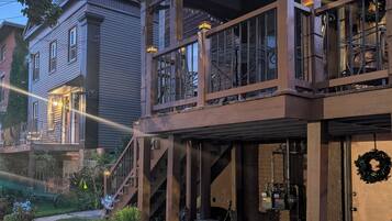 A two-story house with a balcony, a visible garage, and a front yard with plants.