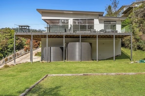 A modern two-story house with a flat roof, large windows, and a covered outdoor area with cylindrical structures. - Wye Not  Panorama Ocean Views (Wye River)