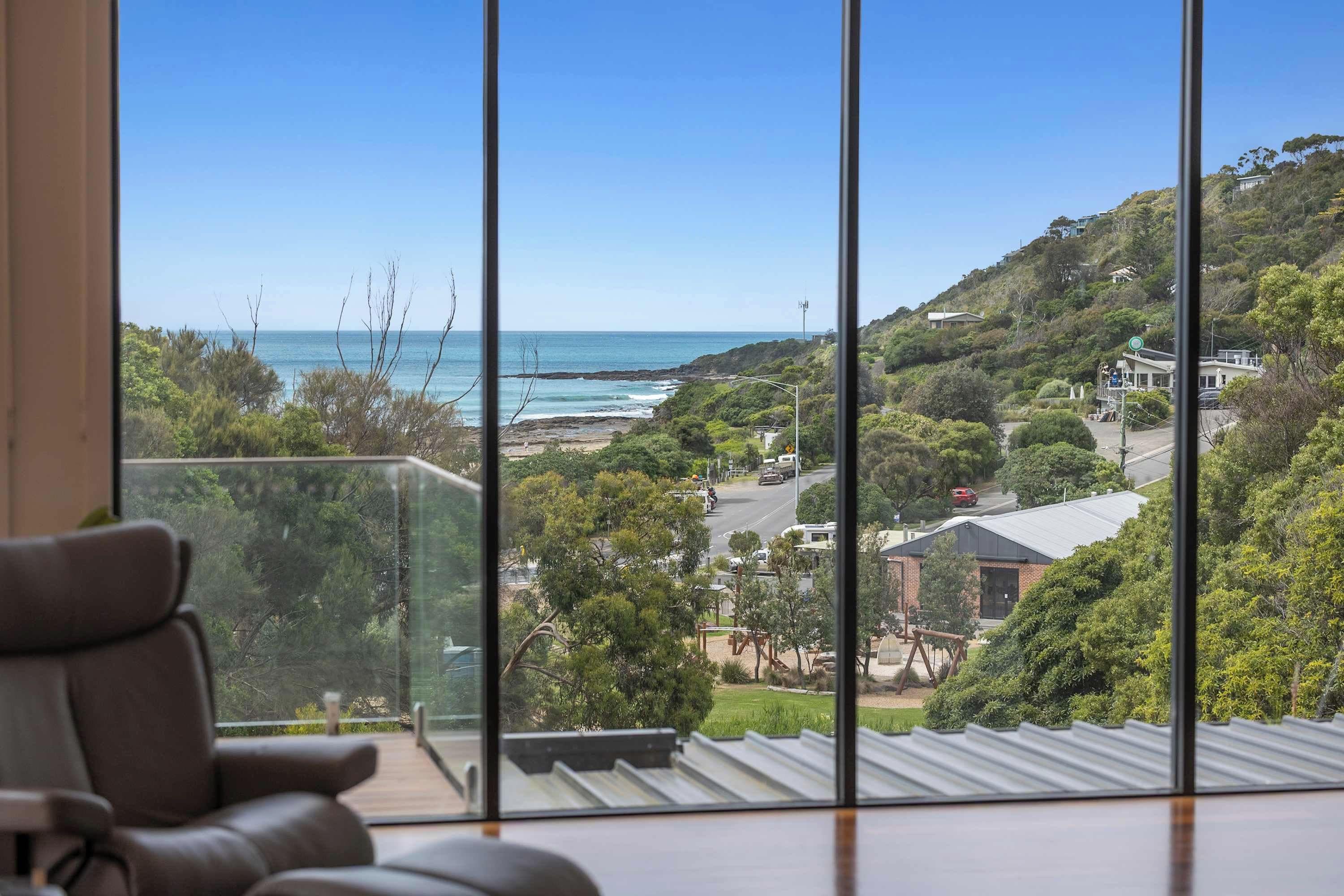 A room with a large window overlooking a coastal landscape, including a beach and hills.