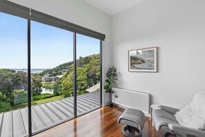A modern living room with a large window, a radiator, a grey sofa, and a framed picture on the wall. - Wye Not  Panorama Ocean Views (Wye River)