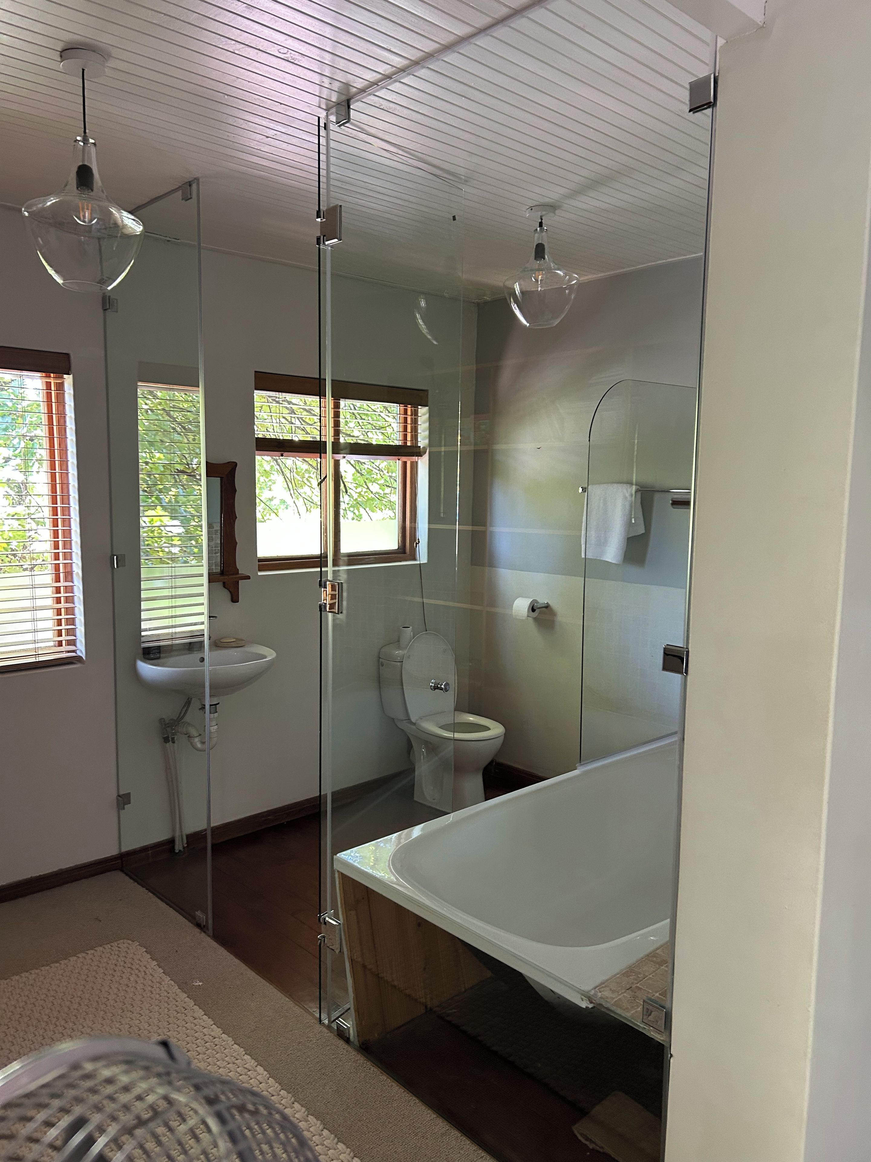 A modern bathroom with a glass shower enclosure, a white bathtub, and a toilet.