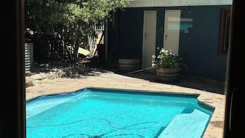 A swimming pool with a tiled edge, surrounded by a stone patio.