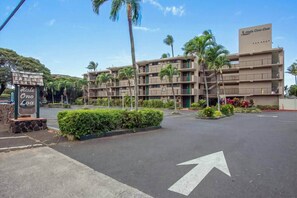 A hotel with a signboard, a parking lot, and a building with multiple floors and balconies. - Oceanfront 1 bedroom West Maui condo, great value, walk to everything (Napili-Honokowai)