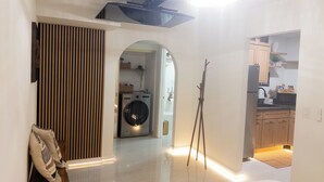 A modern interior with a central hallway leading to a kitchen area, a washing machine, and a coat rack. - Vrbo Property (Glendale)