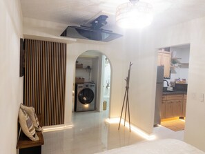 Un intérieur moderne avec un couloir central donnant accès à une cuisine, à un lave-linge et à un porte-manteau.