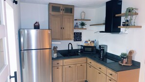 A compact kitchen with a stainless steel refrigerator, wooden cabinets, a microwave, and a coffee maker. - Vrbo Property (Glendale)