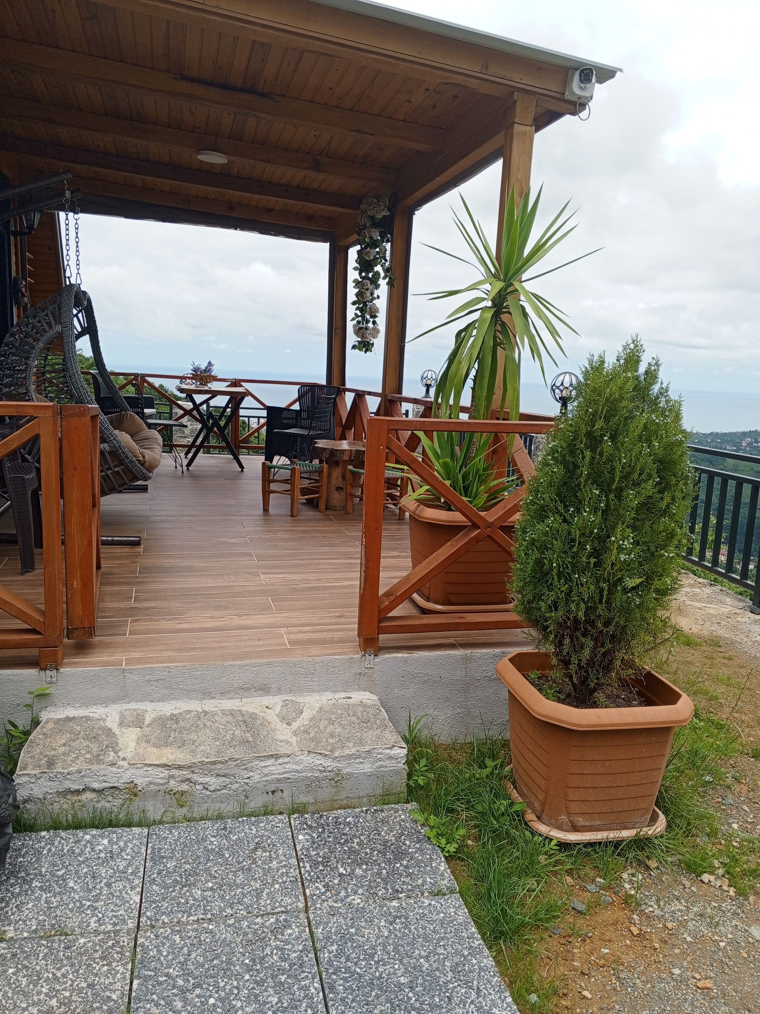 Une terrasse en bois avec des sièges d’extérieur, un pot de fleurs et une vue sur la mer.