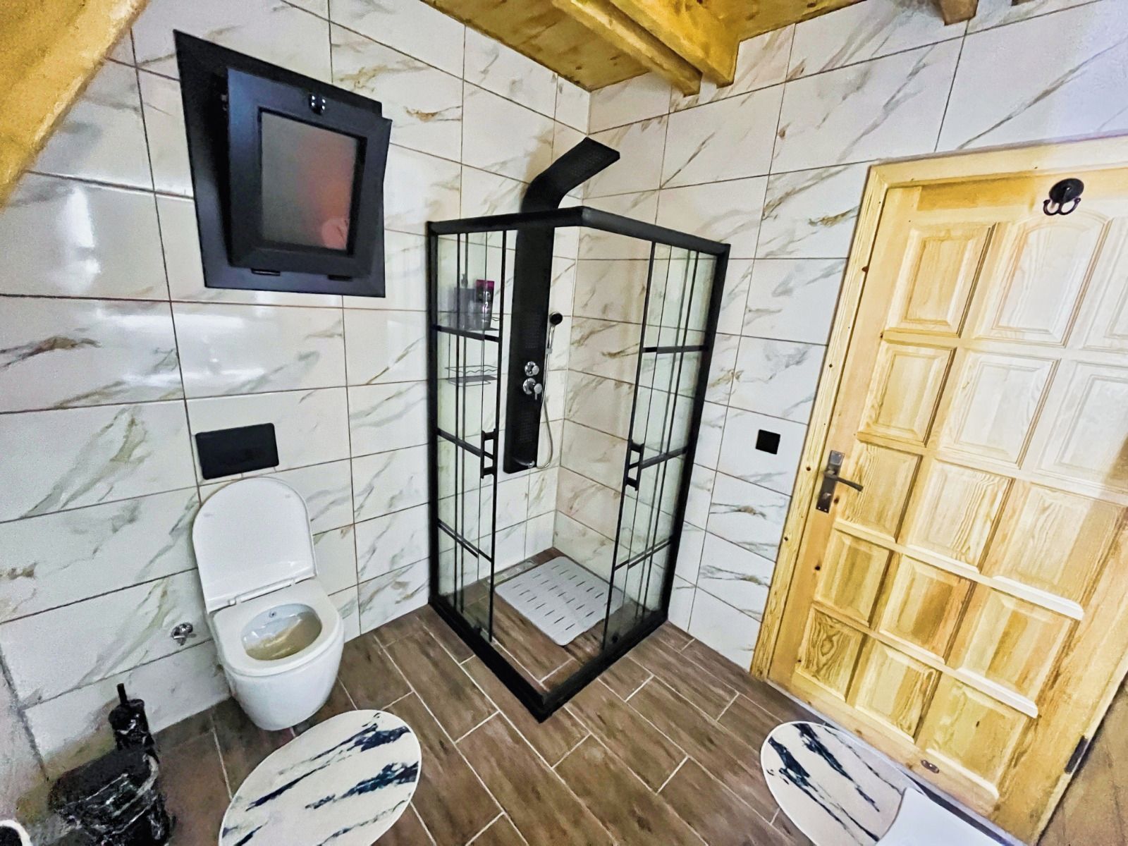Une salle de bain avec une cabine de douche, des toilettes, un lavabo et une porte en bois.
