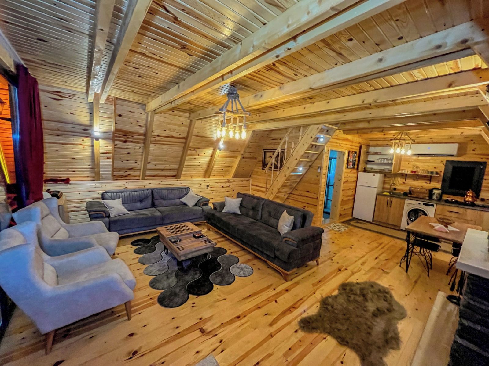 A cozy cabin interior with a living area featuring sofas, a coffee table, and a fireplace.