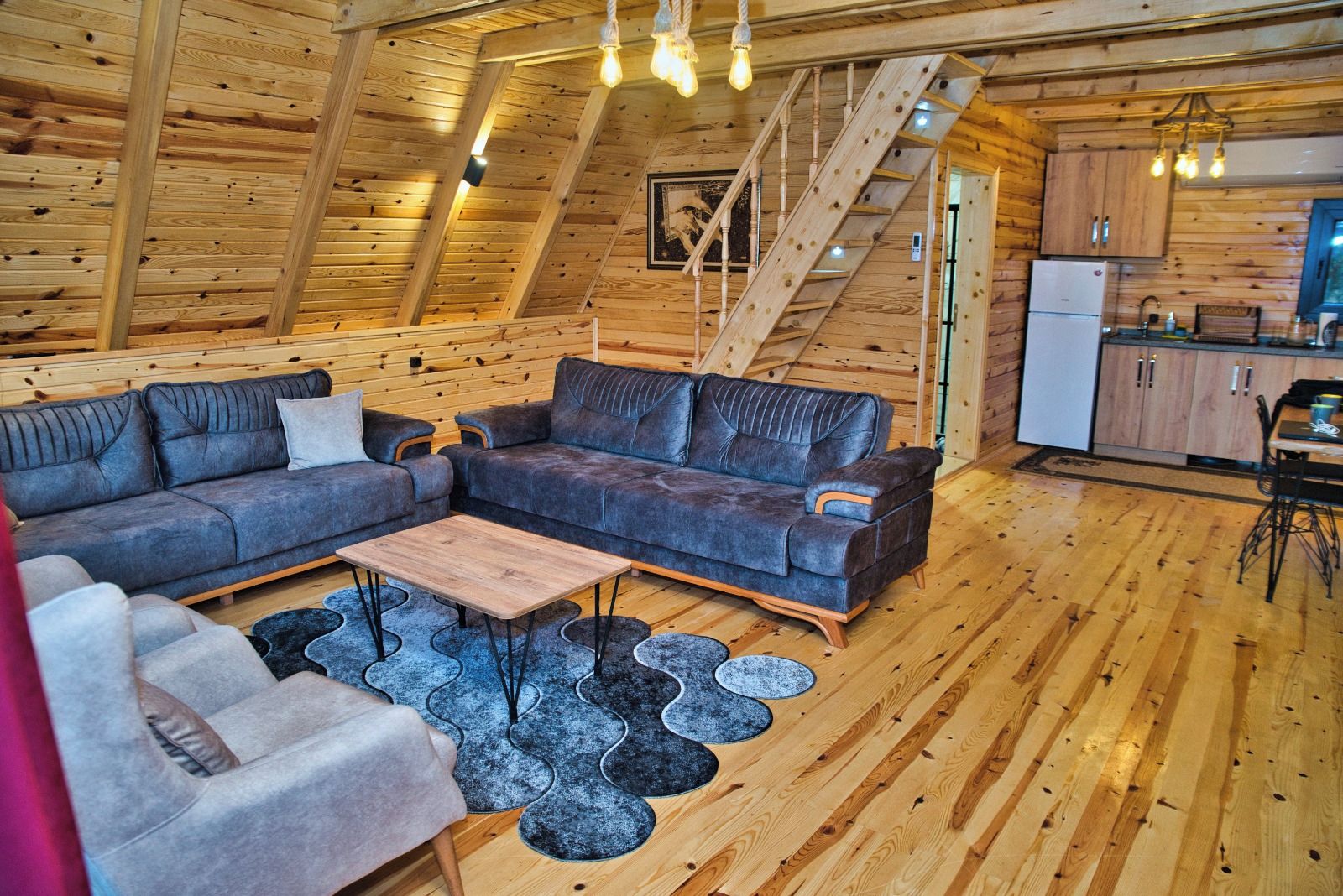 A wooden interior with a sofa set, a coffee table, and a staircase.
