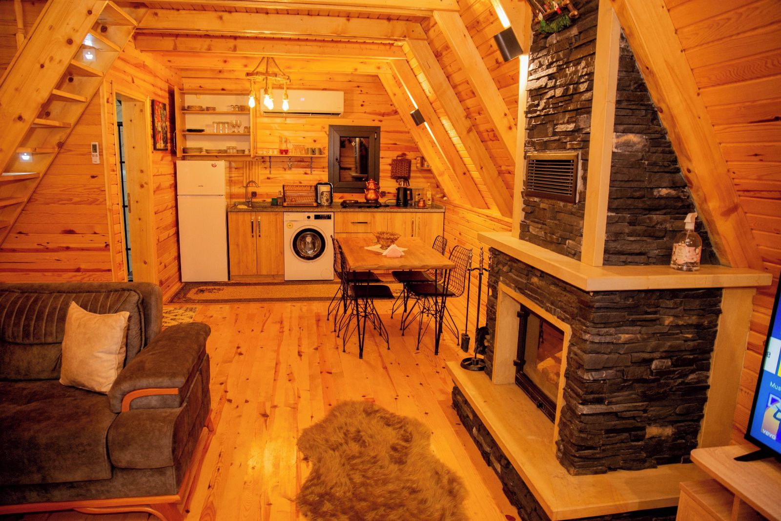 Un intérieur de chalet chaleureux comprenant un coin repas, une cuisine et une cheminée en pierre.