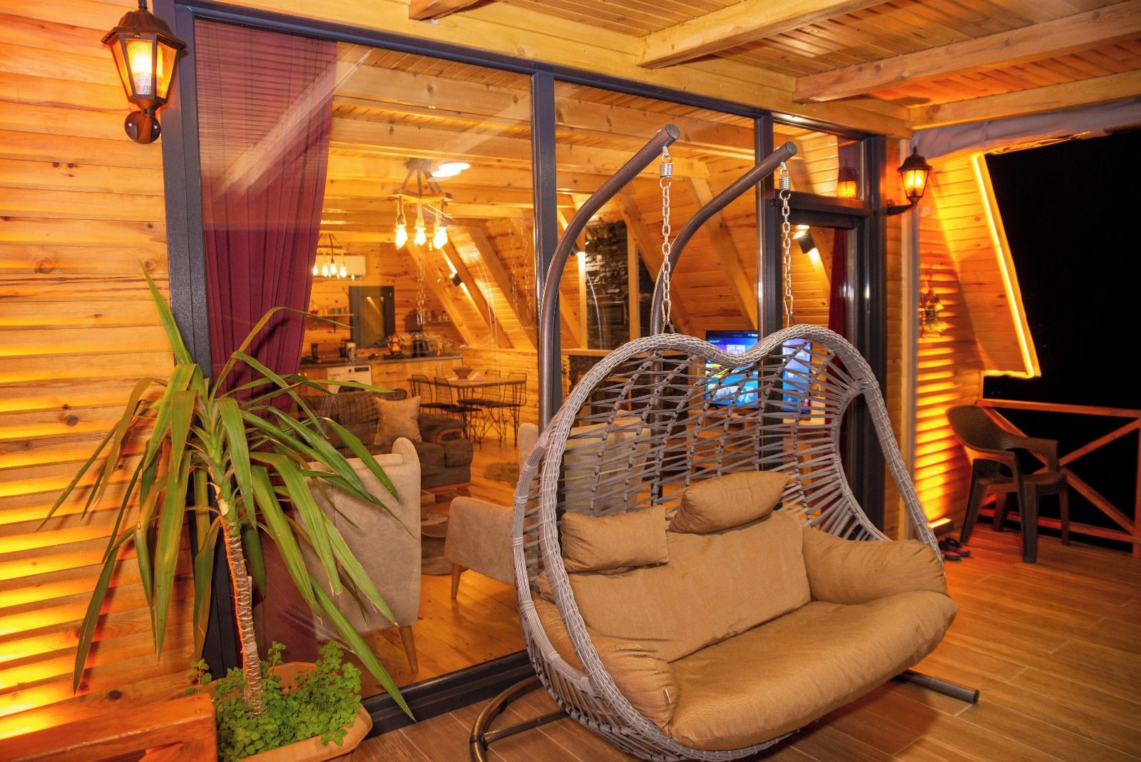 A cozy interior with a hanging chair, wooden walls, and a dining area.