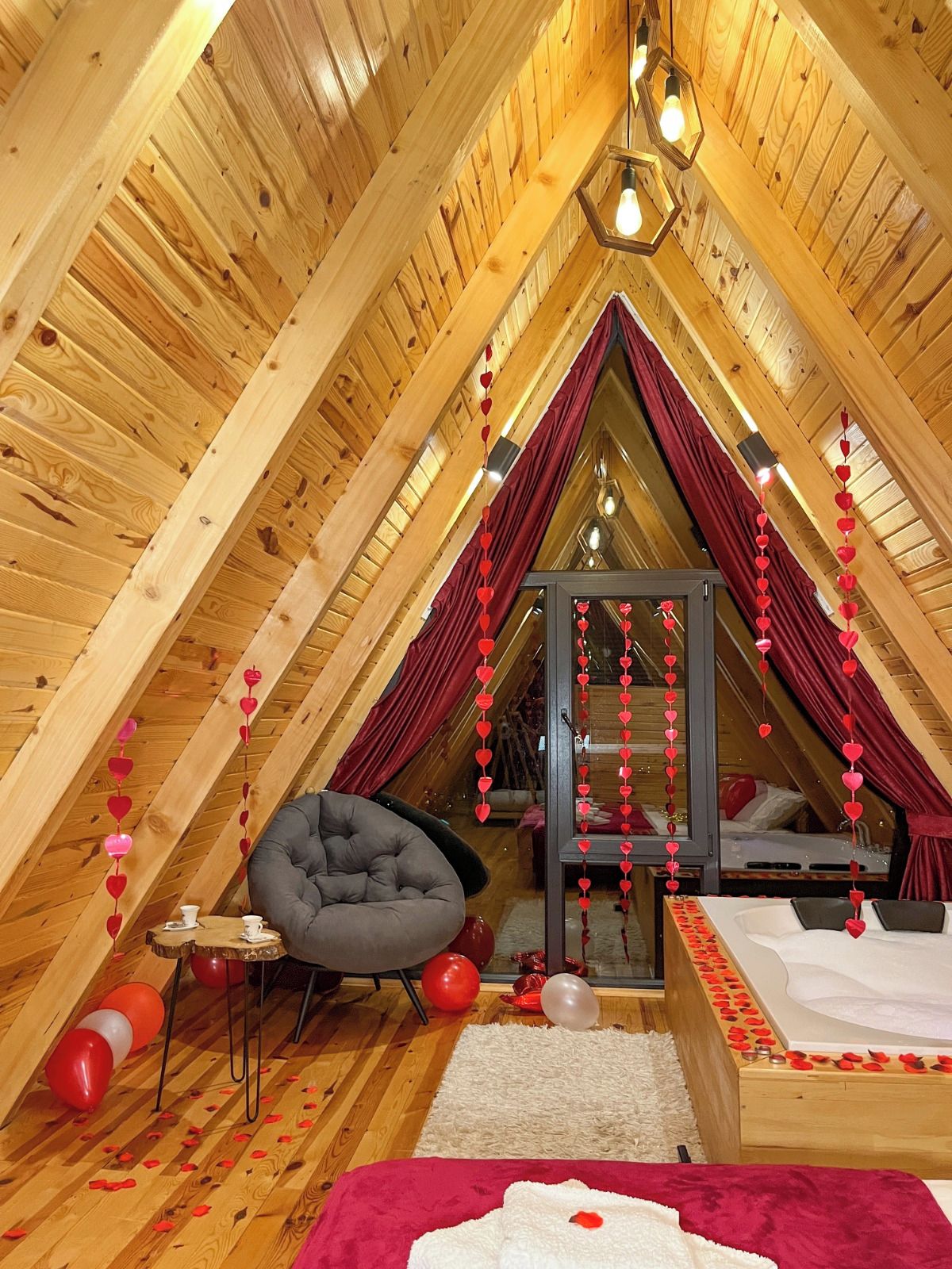 A cozy attic bedroom with a sloped ceiling, a comfortable chair, a bed, and decorative heart-shaped ornaments.