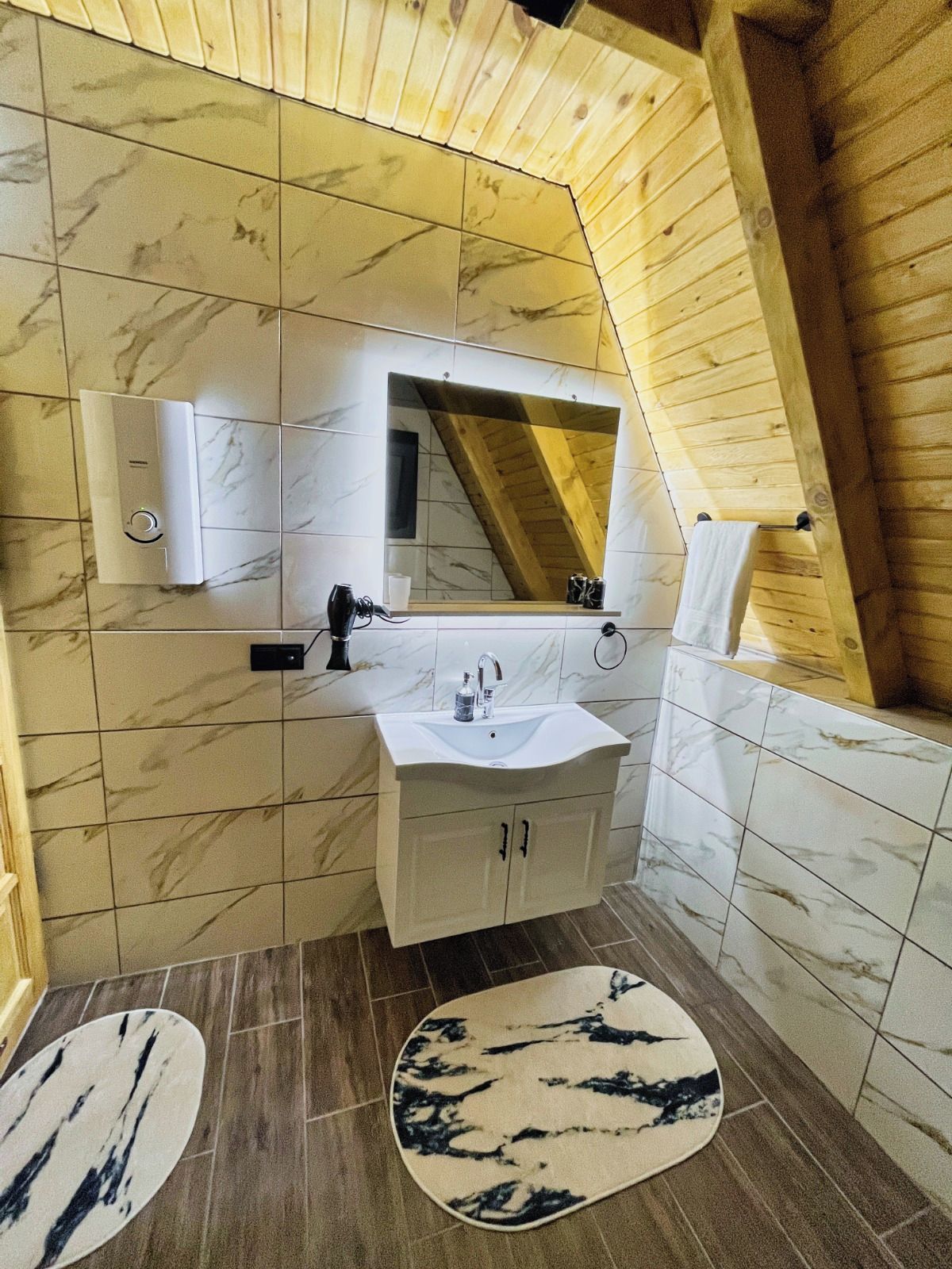 A bathroom with a white sink, mirror, and wooden ceiling.