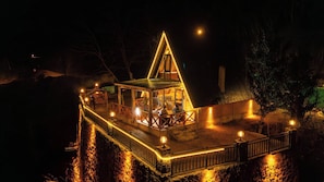A lit, triangular-roofed building with a balcony and a small deck area. - Dere bungalov (Ardeşen)