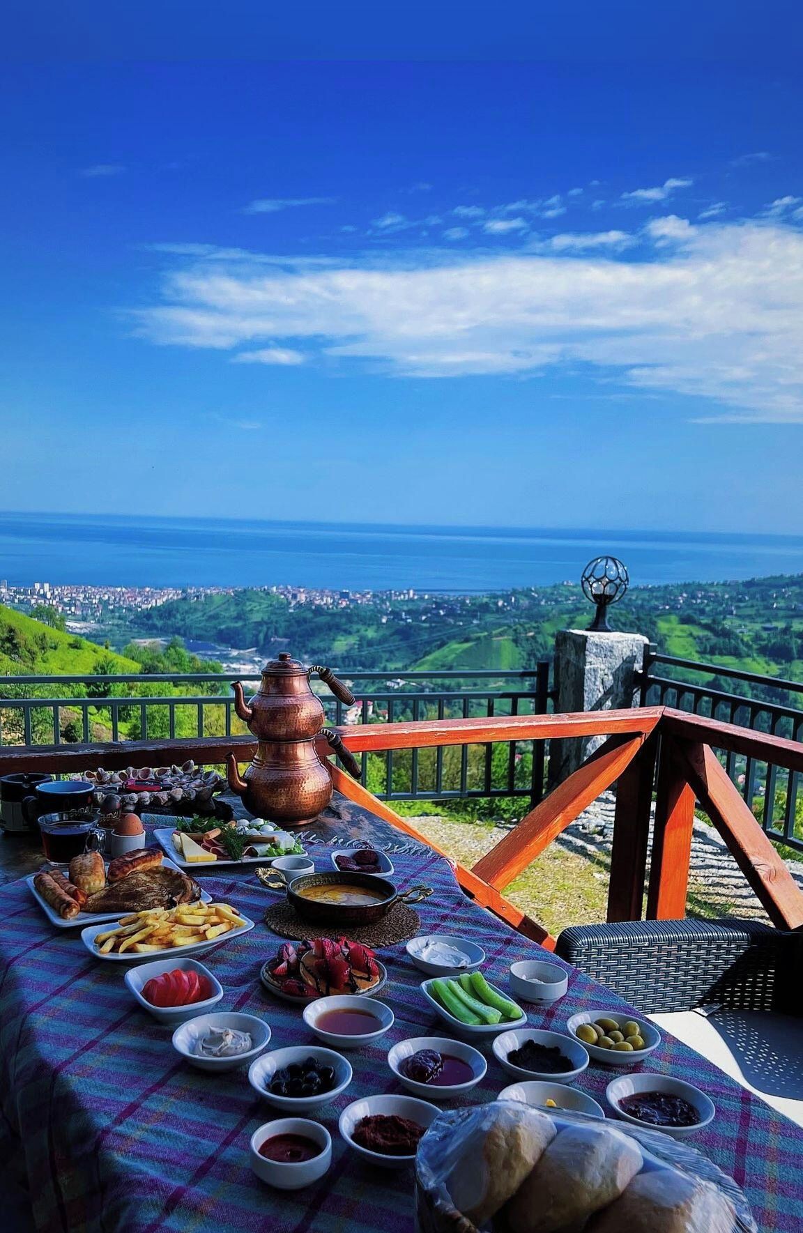 A table set with a variety of food items and a view of a coastal landscape.