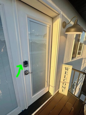 A white door with a frosted glass panel, a green arrow pointing to the door handle, and a 'WELCOME' sign on the porch. - Serene Mountain & Temple View Retreat w/ Hot Tub Access (Riverton)