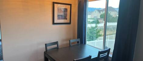 Un comedor con una mesa y sillas, un cuadro en la pared y una ventana con cortinas.