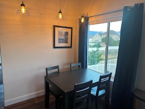A dining area with a table and chairs, a framed picture on the wall, and a window with curtains. - Serene Mountain & Temple View Retreat w/ Hot Tub Access (Riverton)